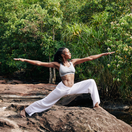 Woman doing yoga on a rocky surface in a lush tropical area